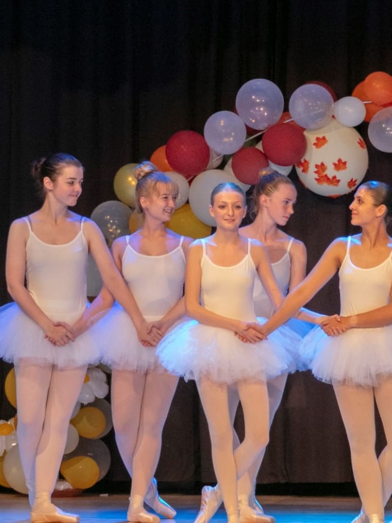 Ballettschülerinnen in weißen Tutus auf der Bühne
